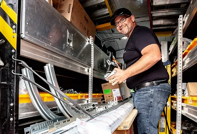 Installateurs de Portes Ro-Ma, à Shawinigan, qui remplissent leur camion pour aller réparer les portes de garage agricoles d'une grange à poteaux d'une ferme de St-Tite